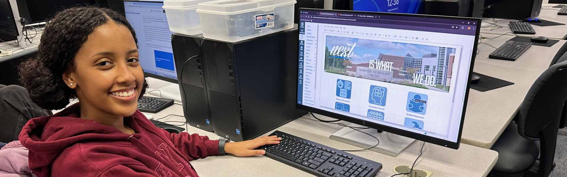 A student smiling at the camera, working on a site.